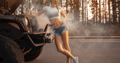 woman in white tank top and blue denim shorts standing on black motorcycle during daytime