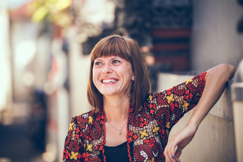 woman in floral-themed cardigan leaning on fence in bokeh photography