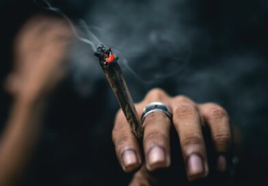 person wearing ring and holding blunt